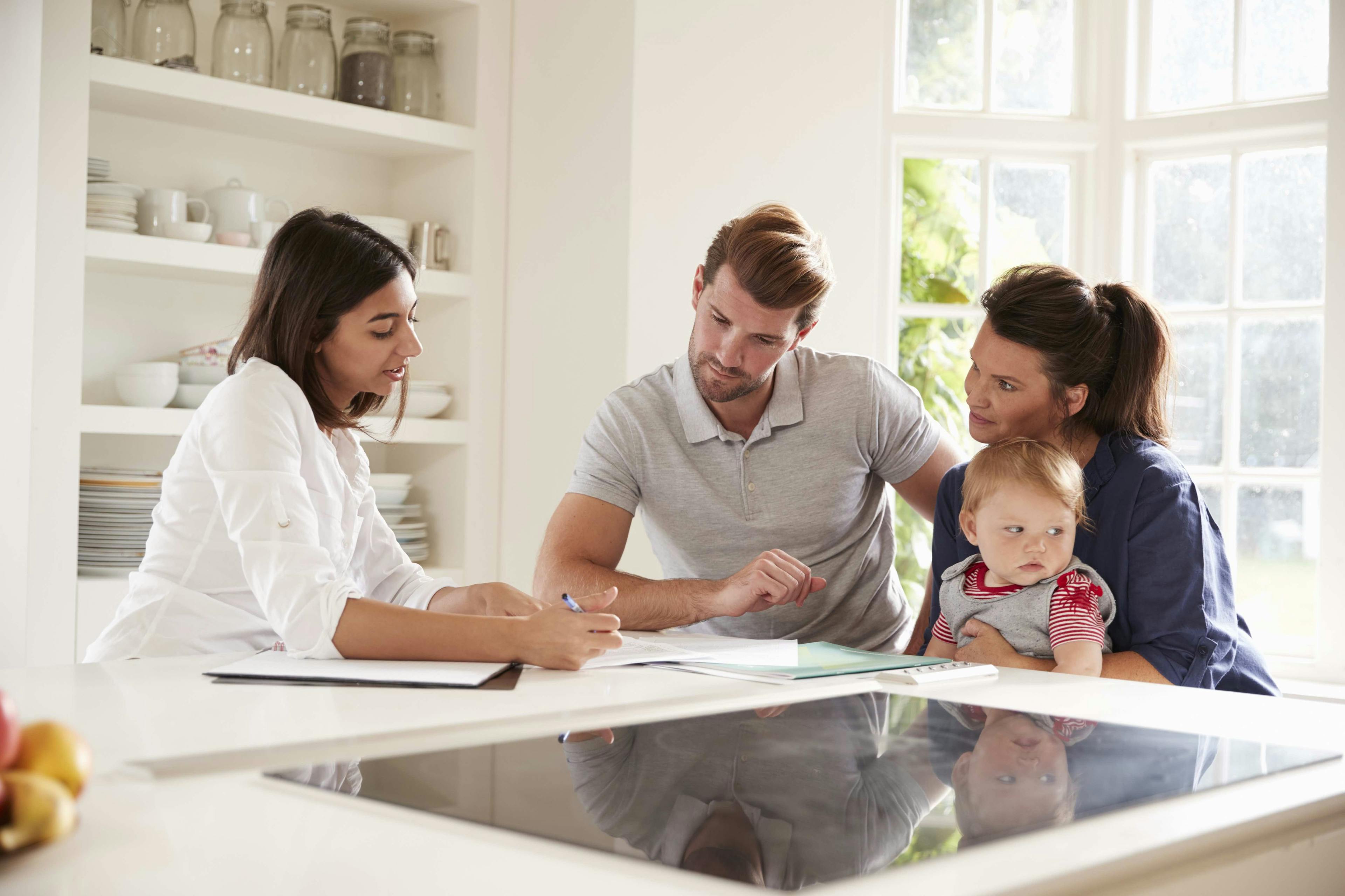 Caucasian parents with daughter, learning from financial advisor at kitchen table