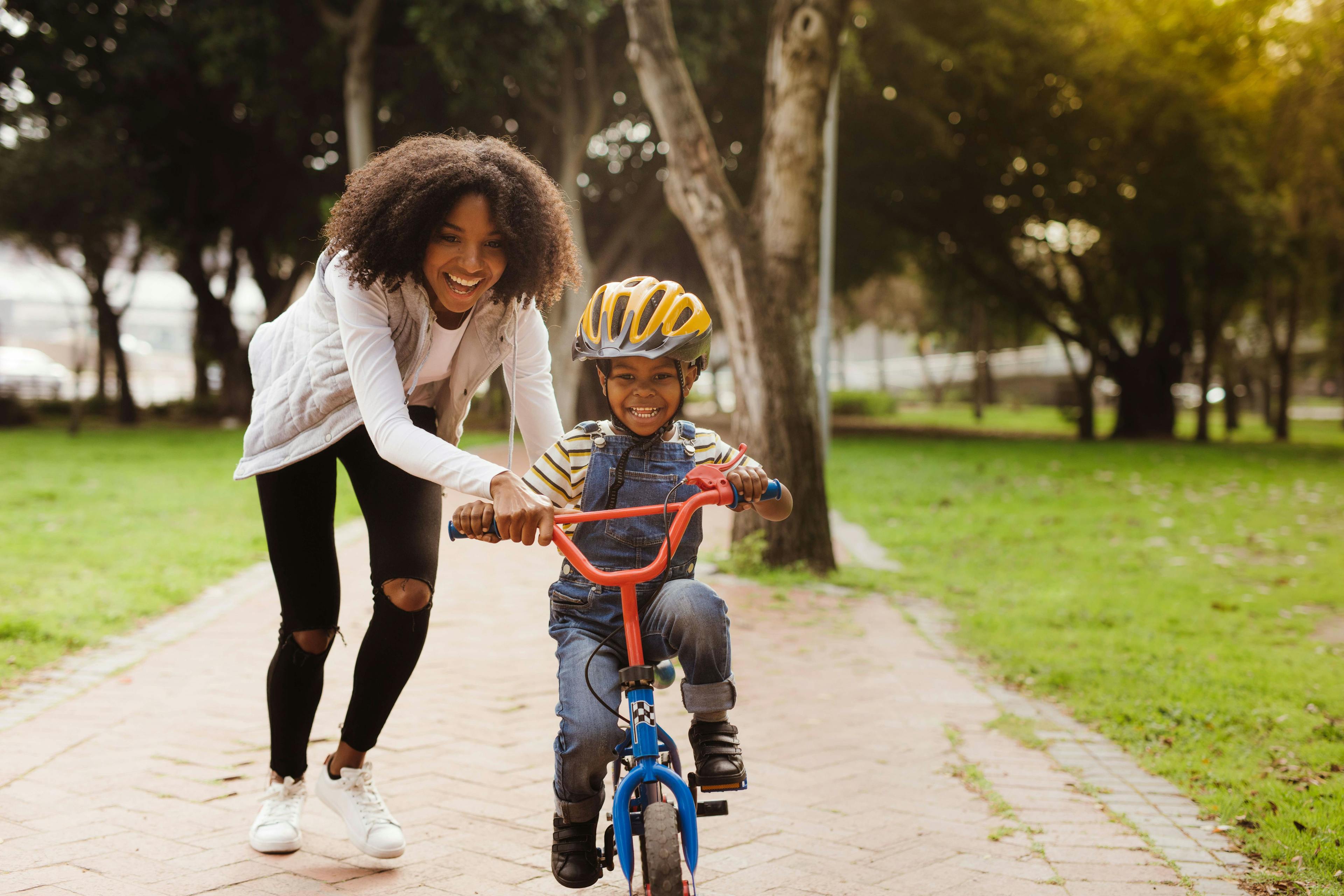 Black single mom smiling, while helping son ride a bike